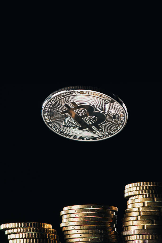 Zamknij widok srebrny bitcoin i stosy na centów na czarnym tle - Zdjęcie, obraz