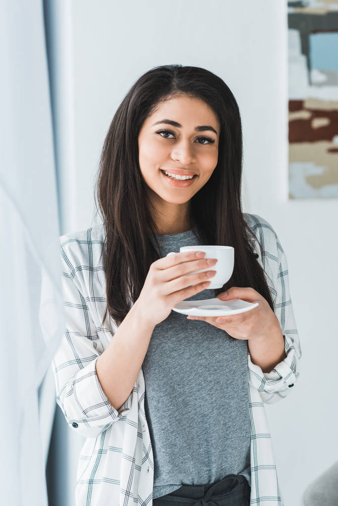 Sonriente mujer afroamericana bebiendo café de taza blanca
 - Foto, Imagen