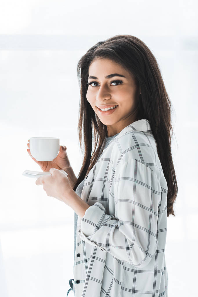 コーヒーのカップを保持している魅力的な女性は笑みを浮かべて - 写真・画像