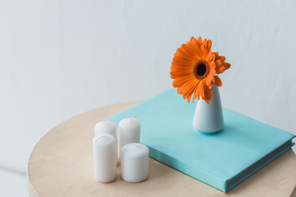 Цветок Герберы и свечи на деревянном столе
 - Фото, изображение