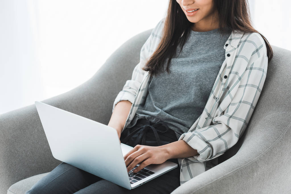 Молодая девушка сидит в кресле и работает на ноутбуке
 - Фото, изображение