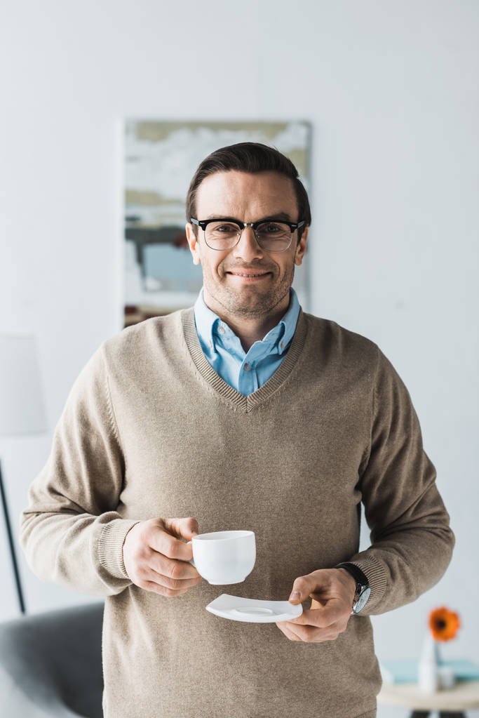 Hombre feliz usando gafas y sosteniendo una taza de café
 - Foto, Imagen