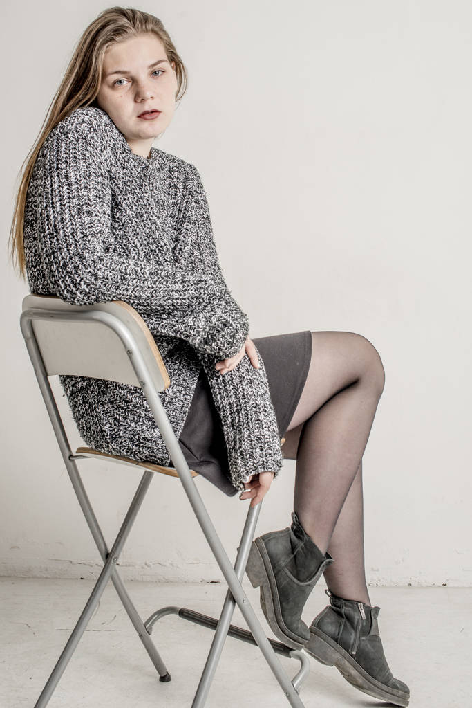 Joven hermosa chica sentada en un suéter gris largo y cálido
 - Foto, imagen