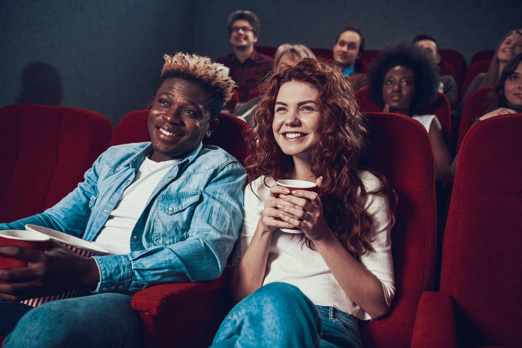 Un hombre con una mujer se sienta en un cine y sonríe. - Foto, imagen