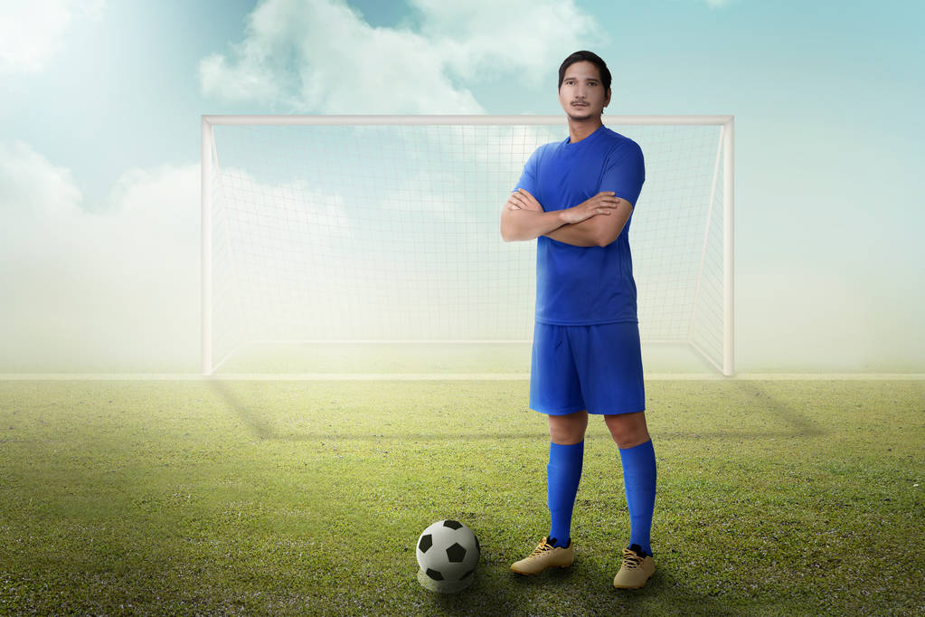 Красивий азіатський футболіст з схрещеною рукою стоїть на полі
 - Фото, зображення