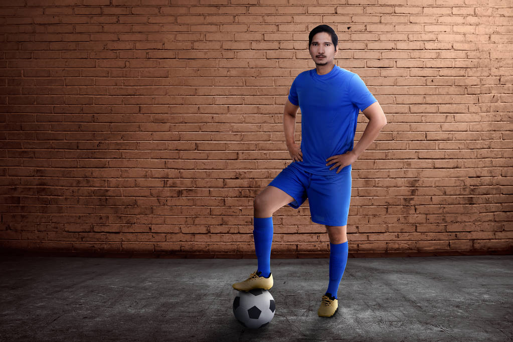 壁の背景と自分の足でボールを持つ若いアジア サッカー プレイヤー - 写真・画像