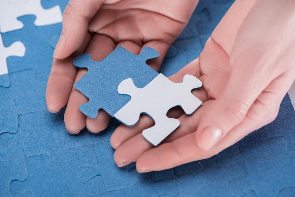 cropped image of businesswoman assembling blue and white puzzles together, business concept - Photo, Image