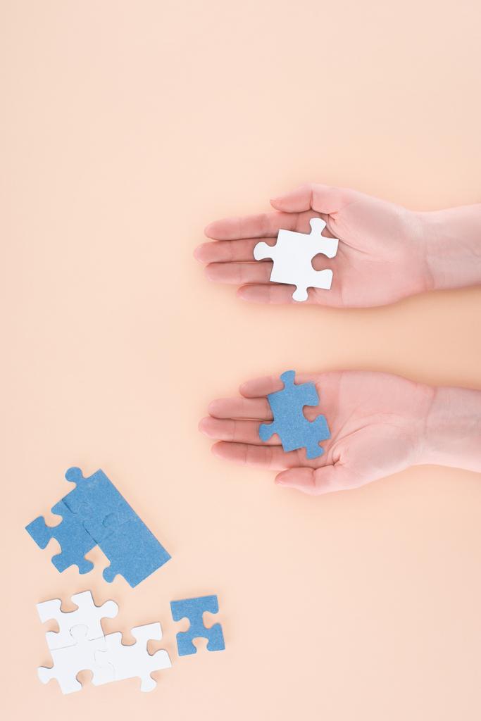 обрезанный образ бизнесвумен с сине-белыми головоломками в руках, изолированных на бежевый, бизнес-концепция
 - Фото, изображение