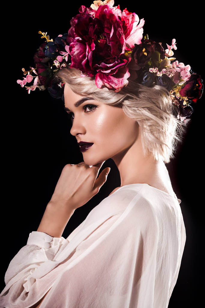 attractive blonde girl with makeup posing in floral wreath, isolated on black - Photo, Image