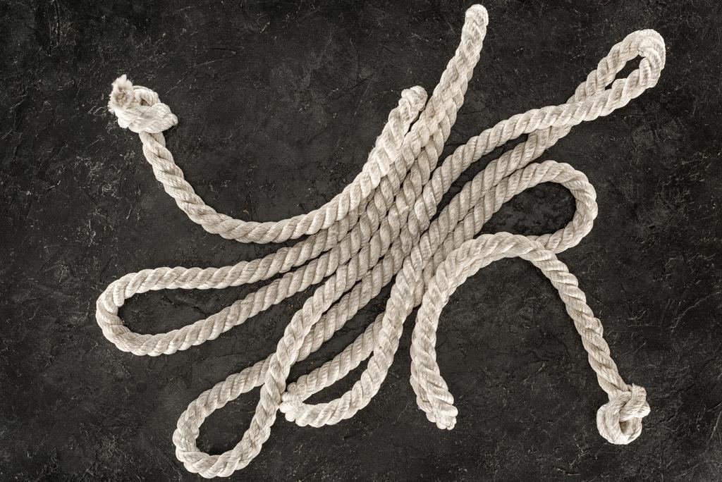 top view of white nautical rope with knots on dark concrete tabletop - Photo, Image