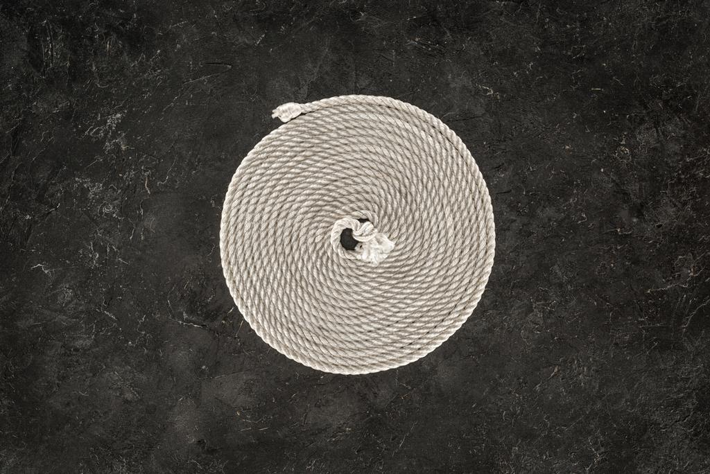 暗いコンクリートの卓上の円に配置された白い航海ロープの上から見る - 写真・画像