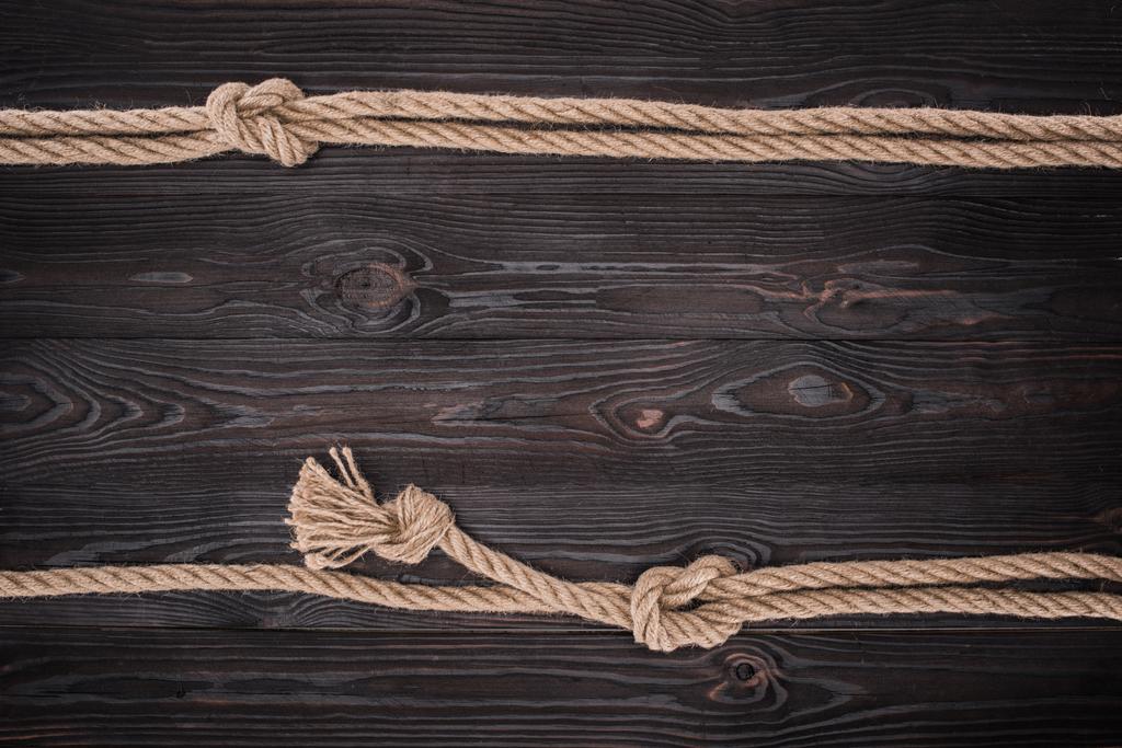 top view of arrangement of brown nautical ropes with knots on dark wooden tabletop - Photo, Image