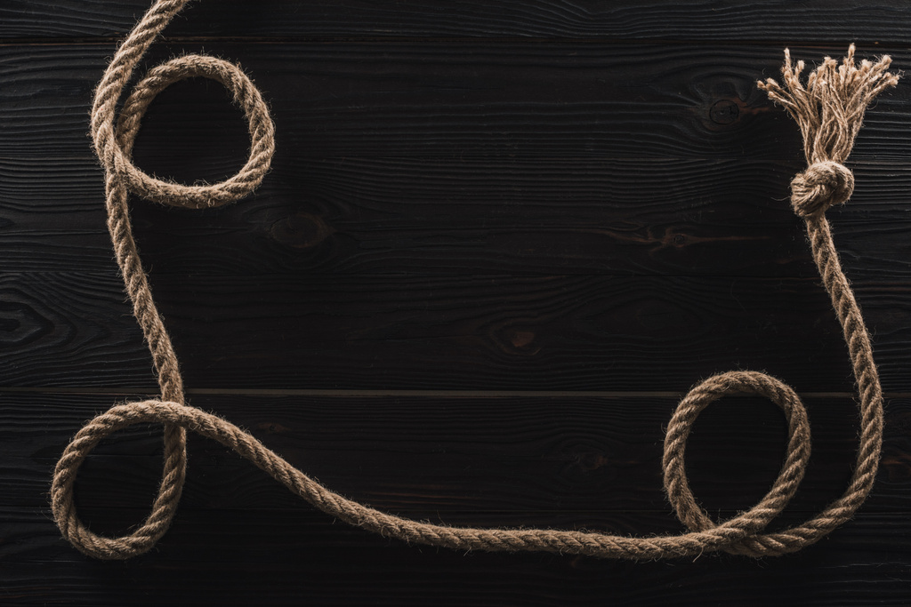 vista superior de cuerda náutica marrón con nudo en superficie de madera oscura
 - Foto, Imagen