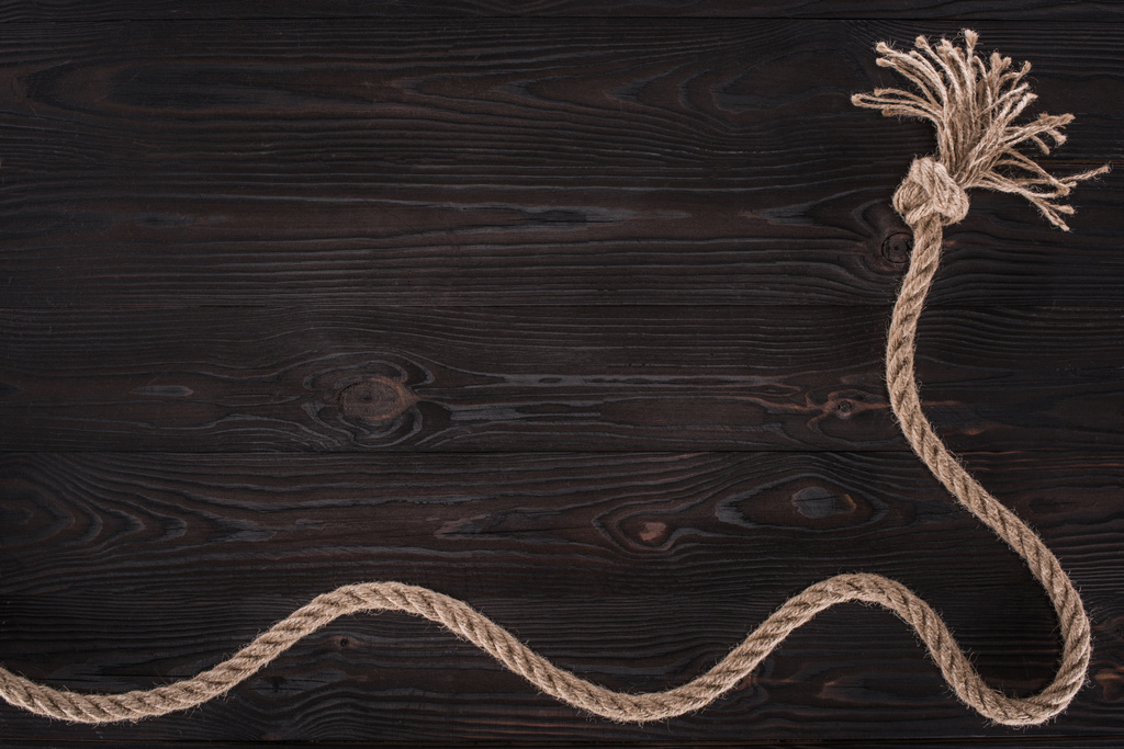 top view of brown nautical rope with knot on dark wooden surface - Photo, Image