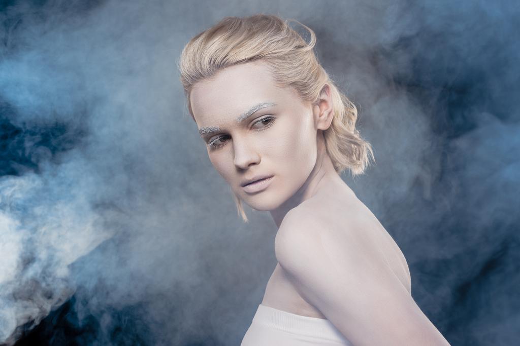 красива блондинка з білим макіяжем позує за модну стрілянину в димчасту студію
 - Фото, зображення