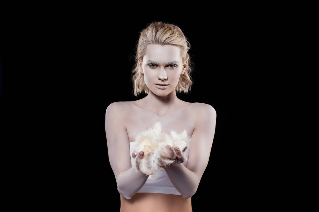 attraktives blondes Mädchen mit weißem Make-up mit Federn, isoliert auf schwarz  - Foto, Bild