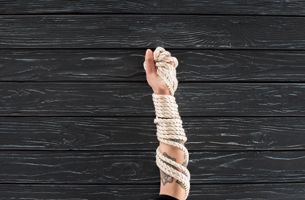 partial view of female hand with marine rope on dark wooden surface - Photo, Image