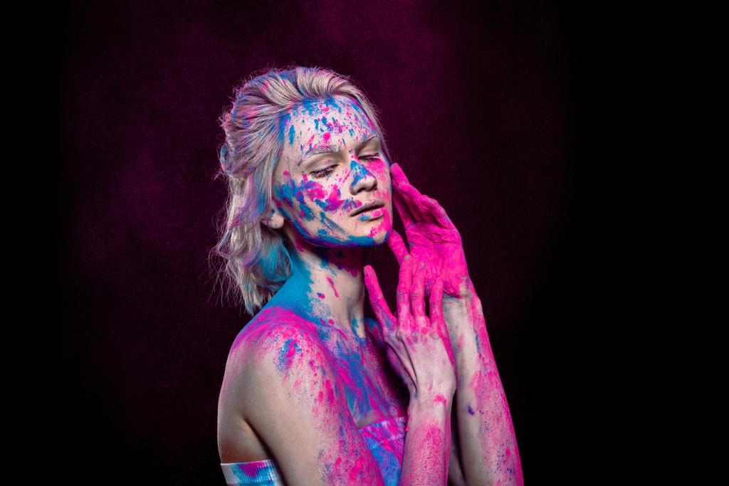 tender girl posing in pink and blue holi powder, isolated on black - Photo, Image