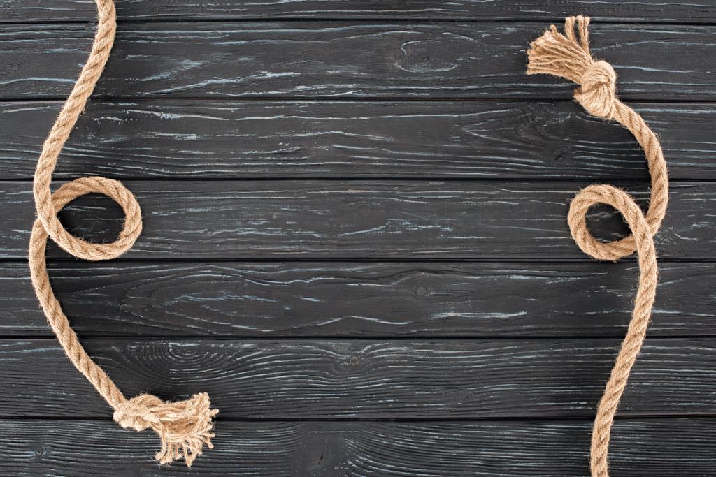 vista superior de cuerdas marrones con nudos en superficie de madera oscura
 - Foto, imagen