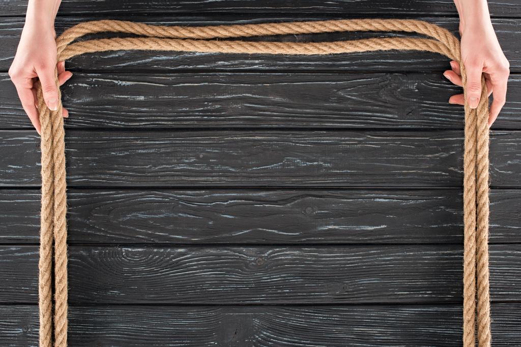 rajattu laukaus nainen tilalla ruskea köydet käsissä tumma puinen pöytälevy
 - Valokuva, kuva
