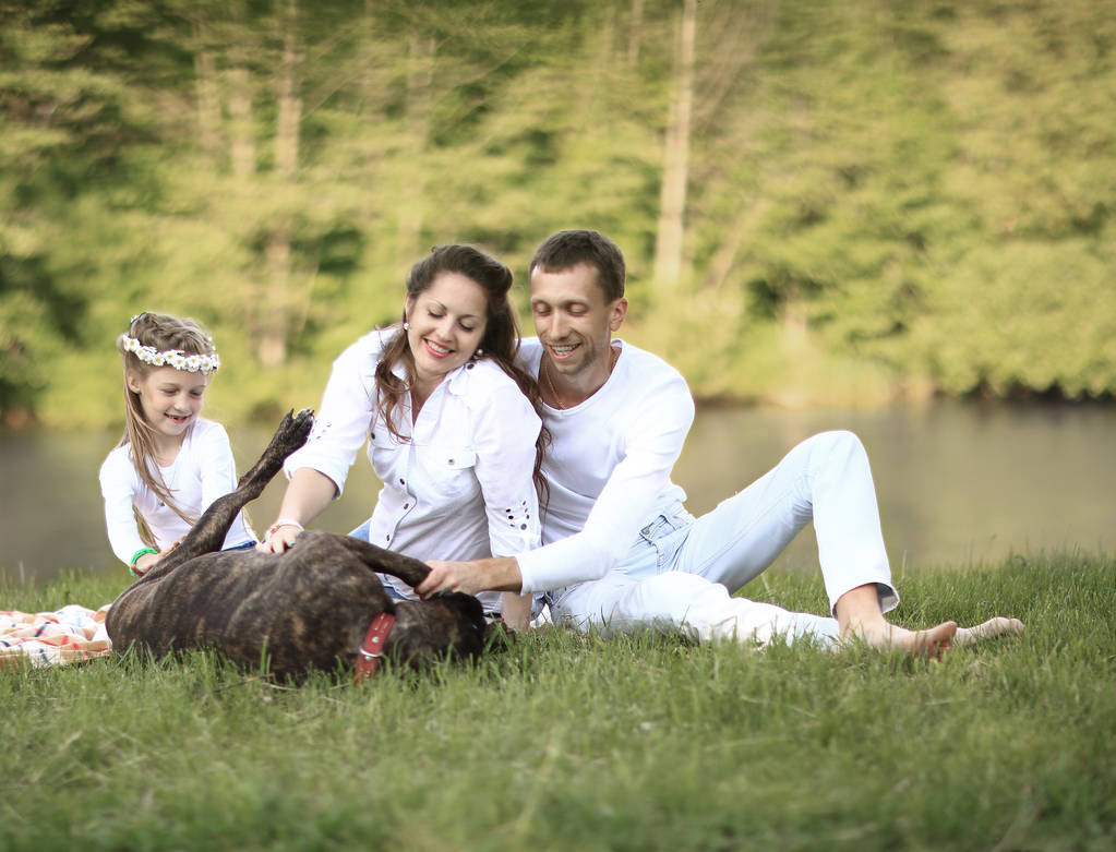 ευτυχισμένη οικογένεια με σκύλο συντροφιάς στο πικνίκ σε μια ηλιόλουστη μέρα του καλοκαιριού. pregn - Φωτογραφία, εικόνα