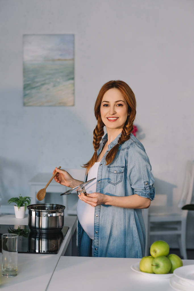 キッチンの電気コンロで料理を魅力的な妊娠中の女性 - 写真・画像