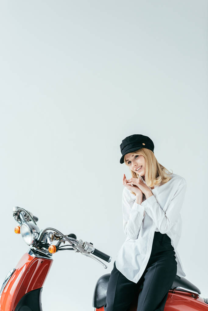 Uśmiechnięta Blondynka siedzi na vintage motocykl na szarym tle - Zdjęcie, obraz