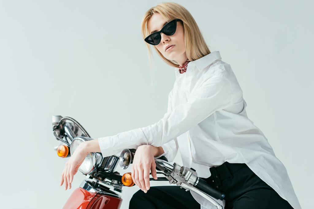 Atractiva joven en gafas de sol en scooter vintage aislado en gris
 - Foto, Imagen