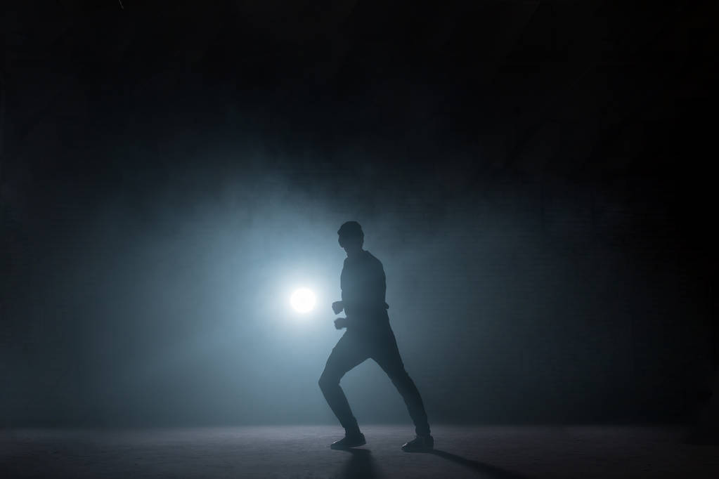 ダンサーは黒い背景に彼の技術を示します。暗闇の中で踊る - 写真・画像