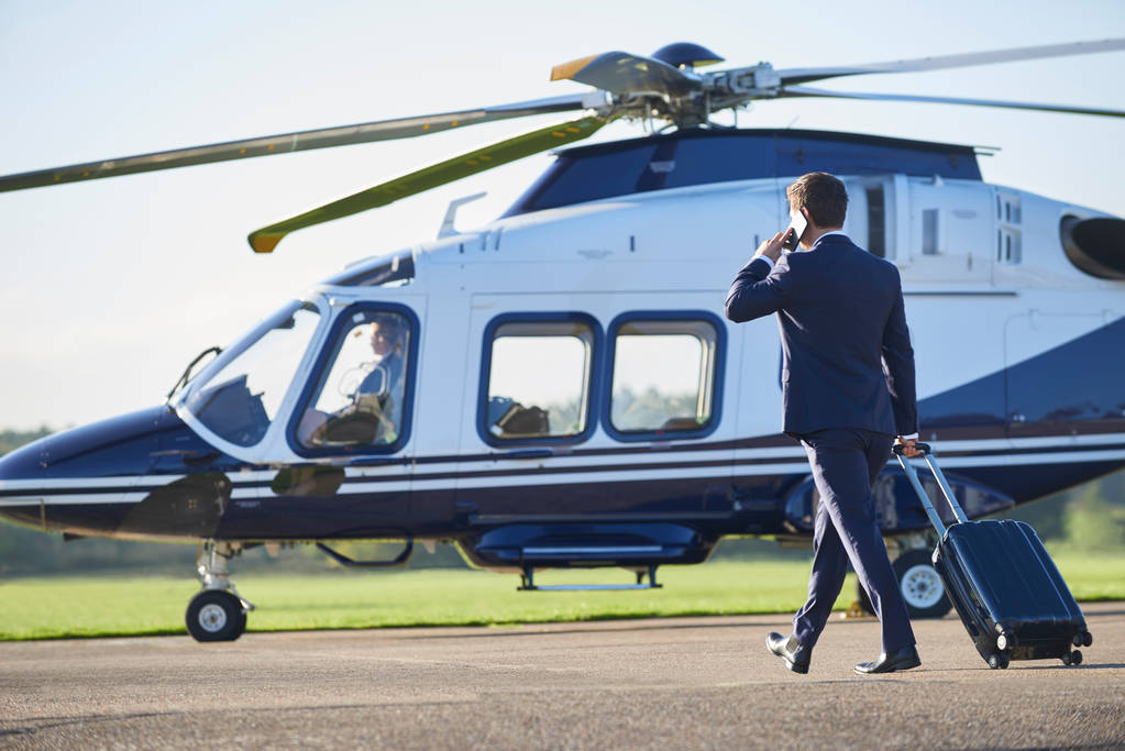 Rear View Of Businessman Walking Towards Helicopter Whilst Talki - Photo, Image