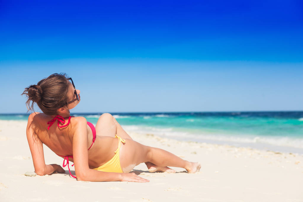 woman in bikini and straw hat lying on tropical beach - Photo, Image