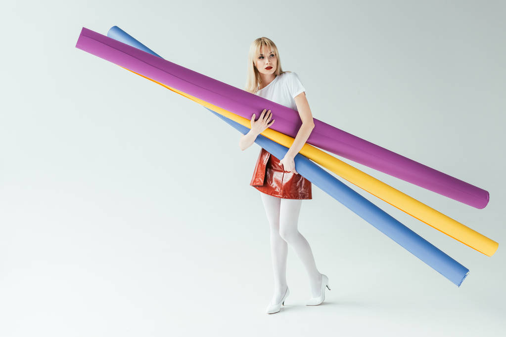 Modieus blond meisje dragen kleurrijke papier rollen - Foto, afbeelding