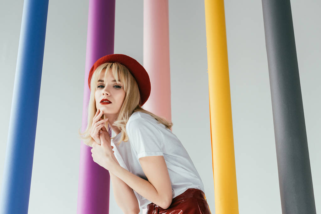 Ładny blond dziewczyna w czerwone i białe ubrania przez kolorowe kolumny - Zdjęcie, obraz