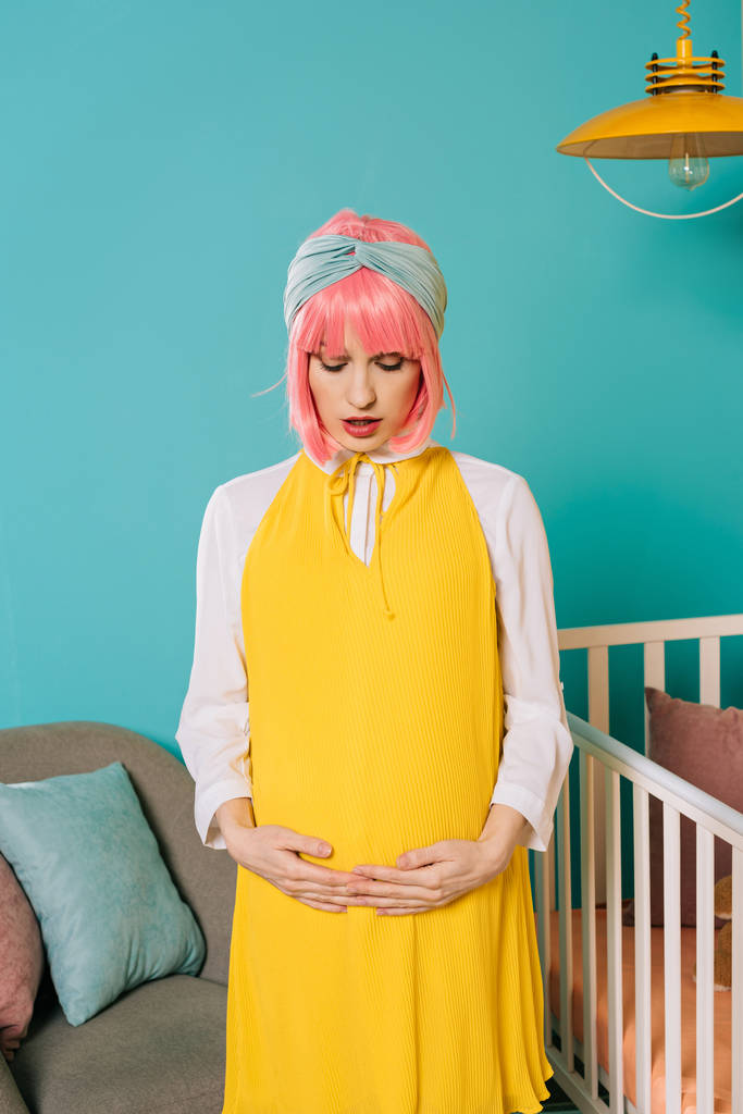 atractivo embarazada pin up mujer con el pelo rosa tocando vientre en habitación de niño
 - Foto, imagen