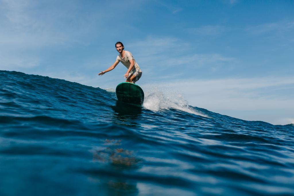 a fiatalember hullámok lovaglás szörf napsütéses napon - Fotó, kép