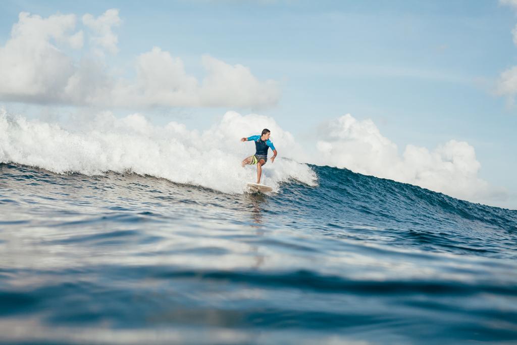 pohledný mladý muž v obleku baví na surfovací prkno na slunečný den - Fotografie, Obrázek