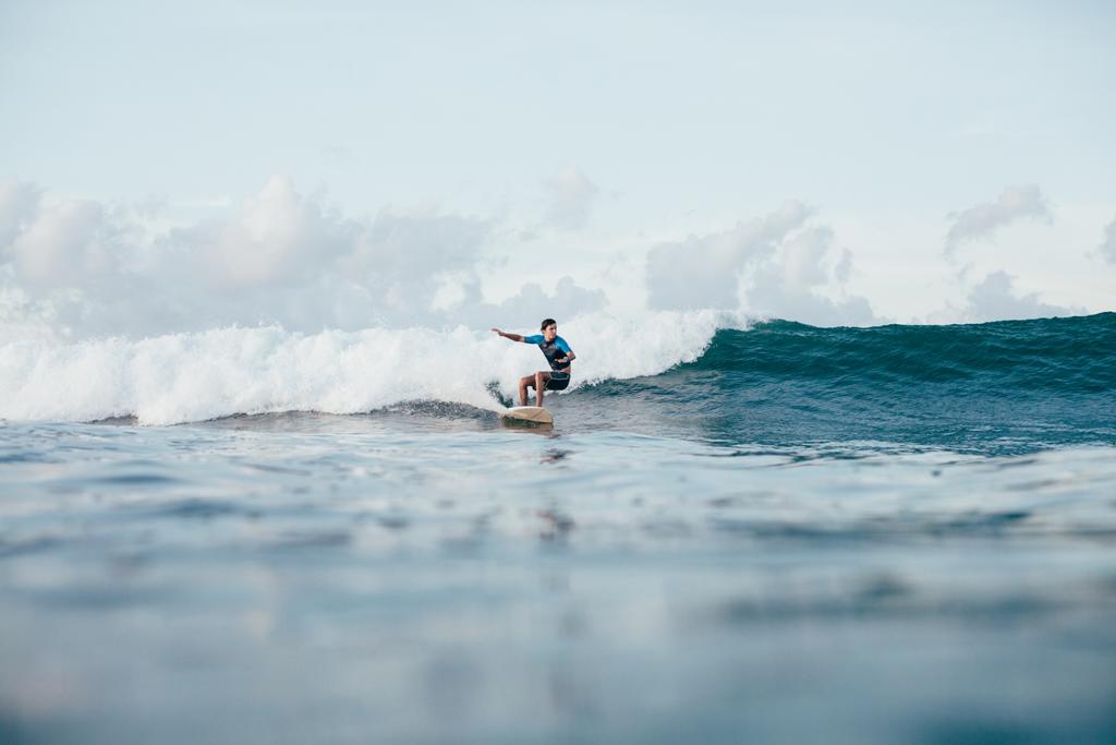 nuori urheilija märkäpuvussa ratsastus aallot surffilauta aurinkoisena päivänä
 - Valokuva, kuva