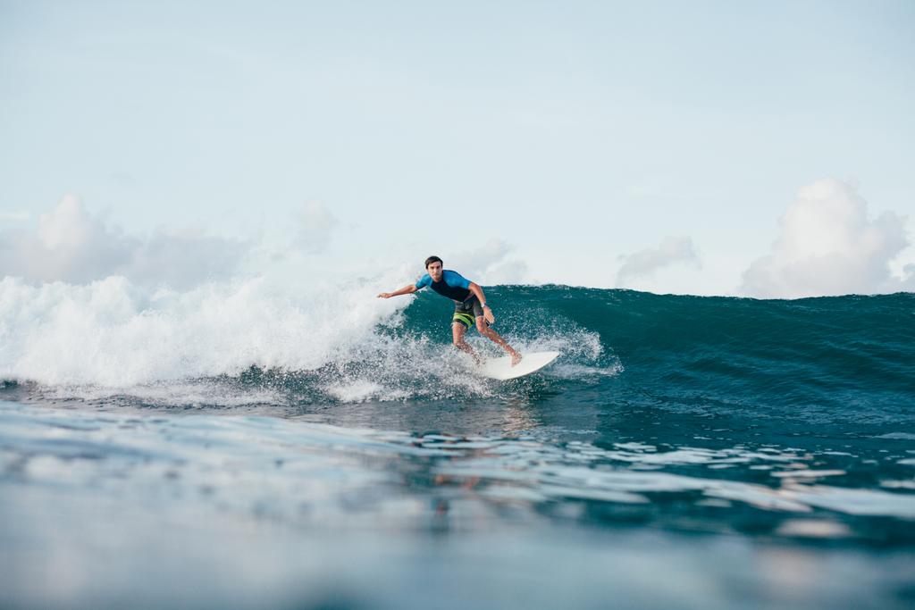 joven en traje de neopreno montando olas en la tabla de surf en un día soleado
 - Foto, imagen