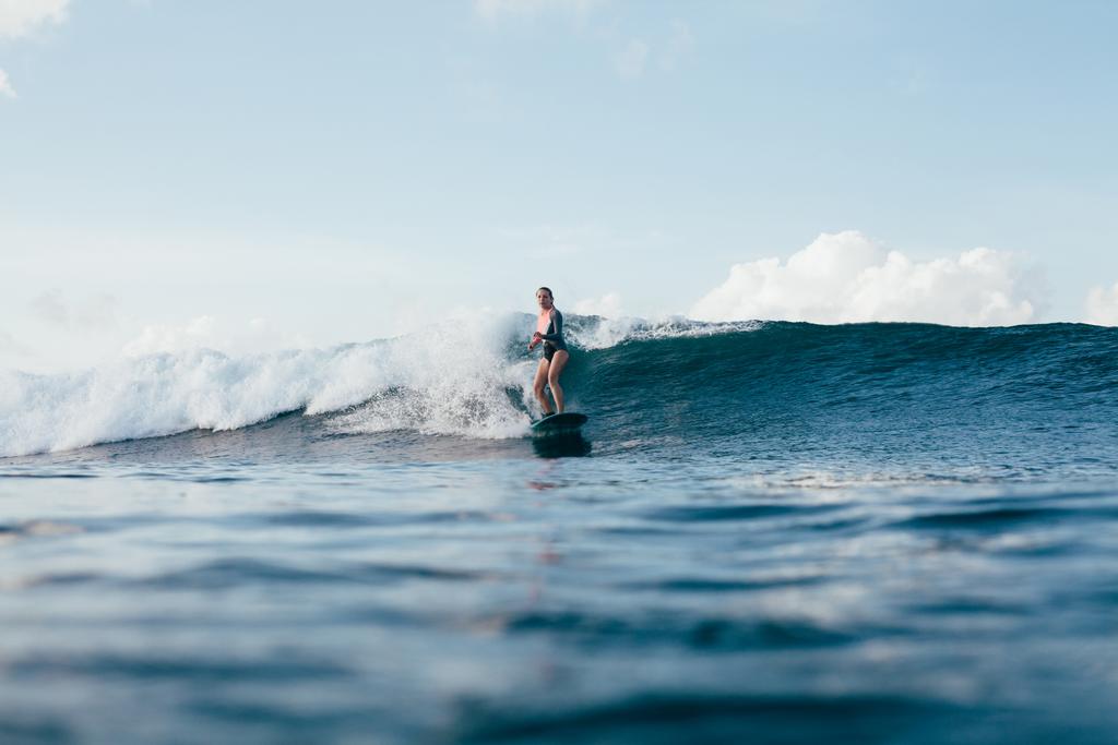 Młoda kobieta w kombinezon surfing na słoneczny dzień - Zdjęcie, obraz