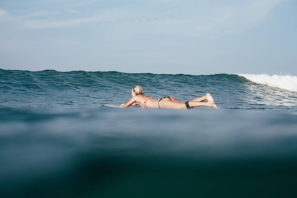 junge Frau schwimmt im Bikini auf Surfbrett - Foto, Bild