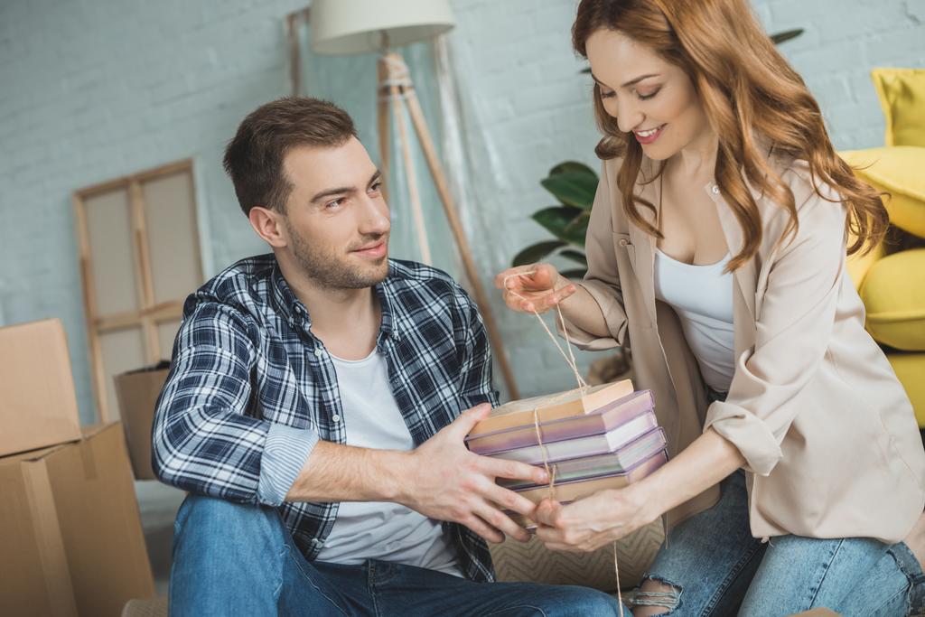 glückliches junges Paar packt Bücher beim Umzug - Foto, Bild