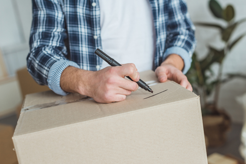 обрізаний знімок чоловіка, що підписує картонну коробку для переїзду додому, концепція переміщення
 - Фото, зображення