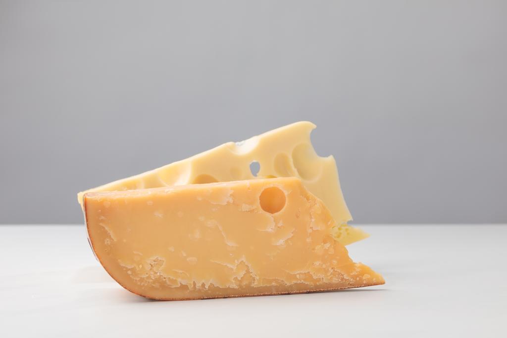 Vista de cerca del queso parmesano y maasdam en gris
 - Foto, Imagen