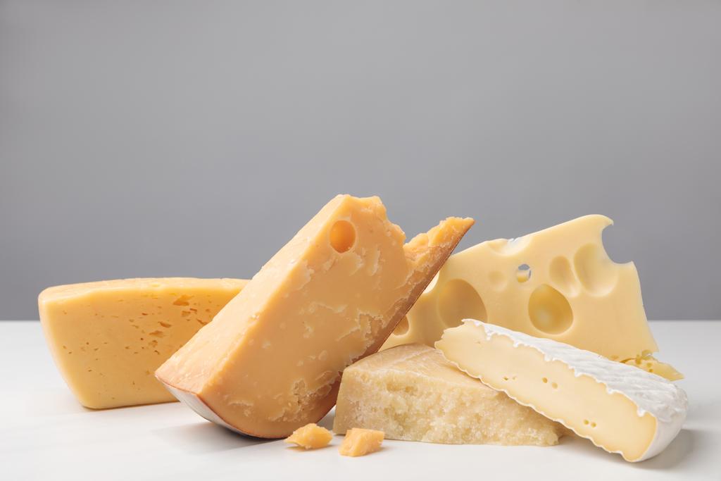 Close-up shot van verschillende soorten kaas op grijs - Foto, afbeelding