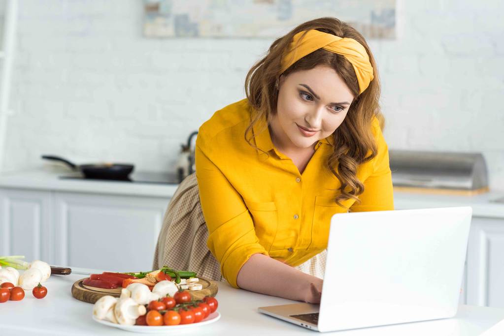 Красива жінка використовує ноутбук на кухні
 - Фото, зображення