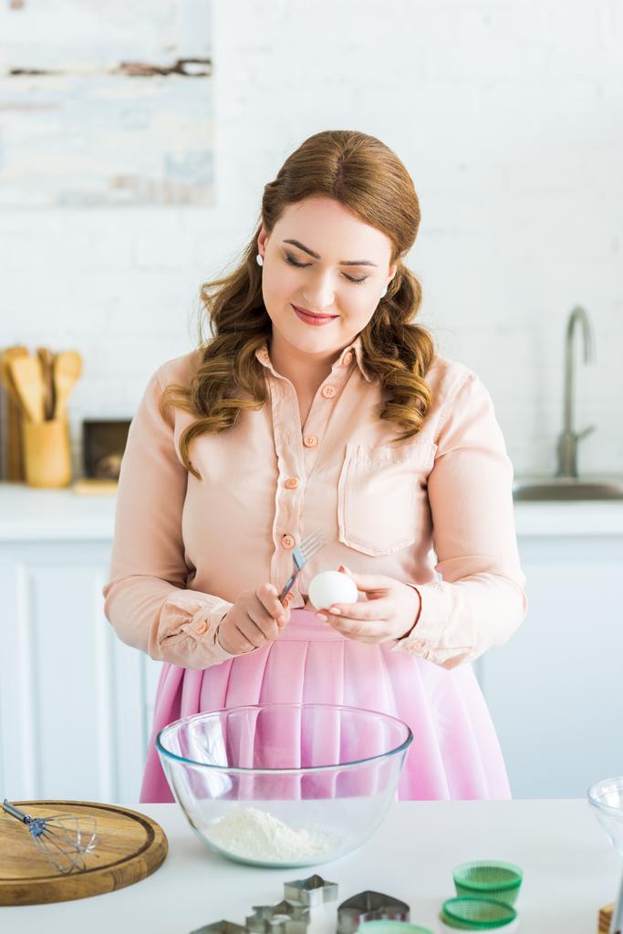 bela mulher quebrando ovo para massa de farinha na cozinha
 - Foto, Imagem