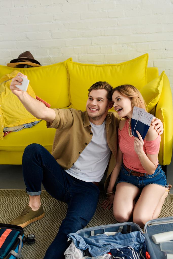 junges Paar macht Selfie mit Smartphone und hält Pässe und Flugtickets in der Hand - Foto, Bild