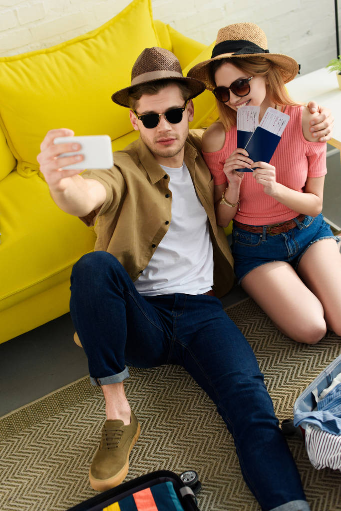 couple in sunglasses with passports and air tickets taking selfie on smartphone - Photo, Image