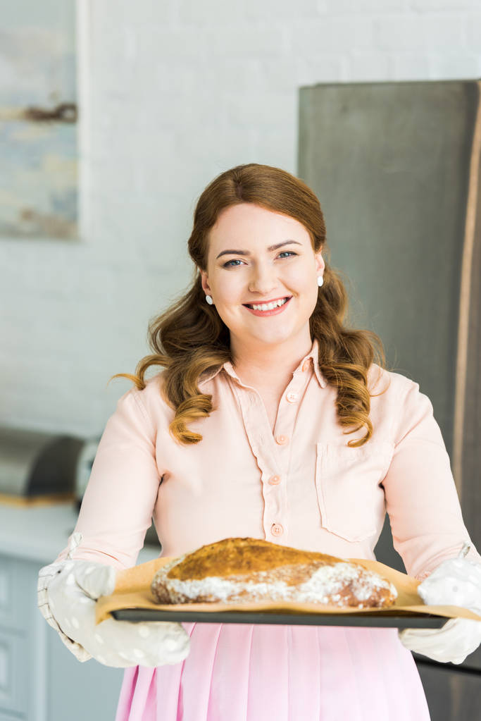 όμορφη γυναίκα που κρατά θήκη με φρέσκο σπιτικό καρβέλι ψωμί στην κουζίνα - Φωτογραφία, εικόνα
