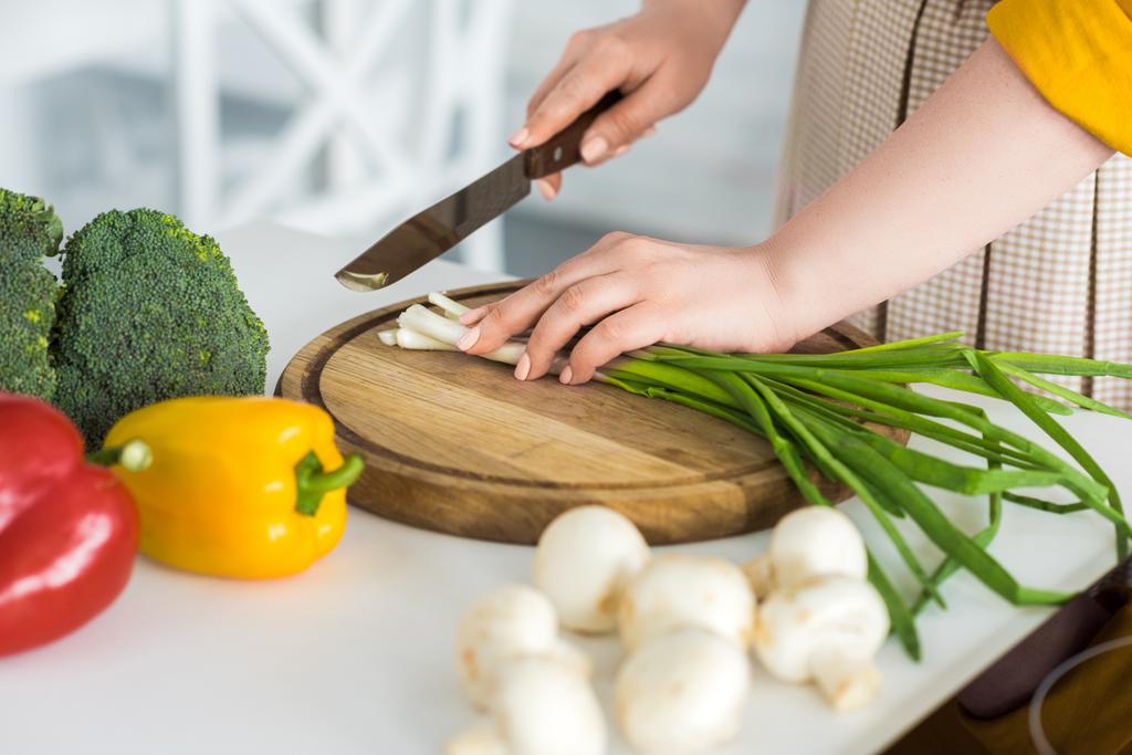 imagen recortada de la mujer cortando cebolla verde en la tabla de cortar
 - Foto, imagen